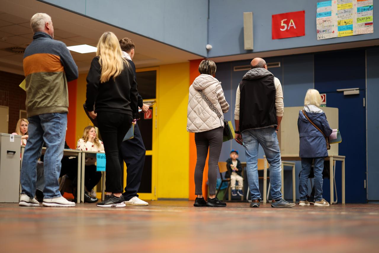In einem Wahllokal in Duisburg-Neumühl stehen Menschen und warten auf eine freie Wahlkabine