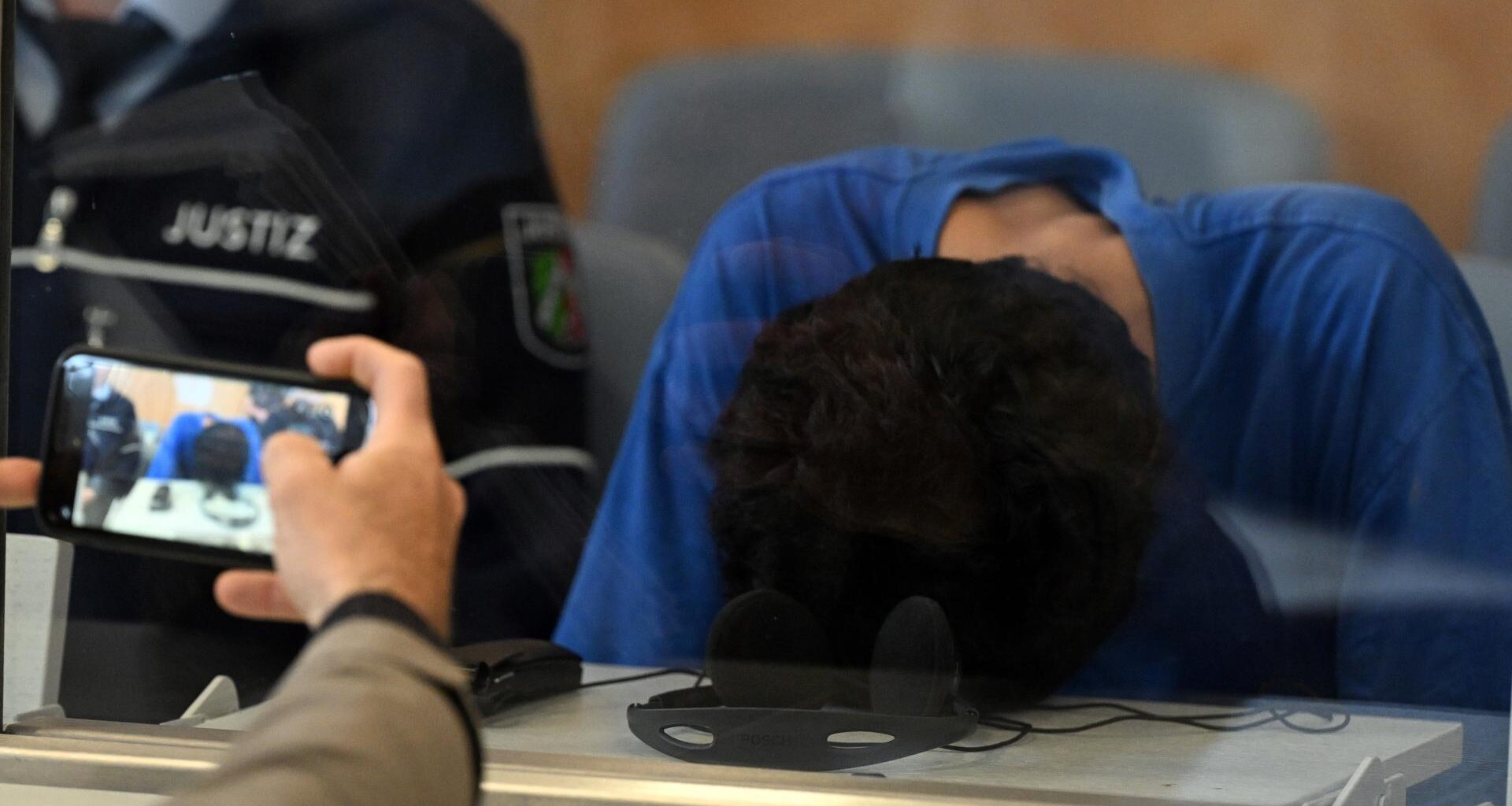 Düsseldorf: Der Angeklagte im Gerichtssaal der Oberlandesgerichts. Er hat den Kopf auf den Tisch gelegt, damit man sein Gesicht nicht sieht.