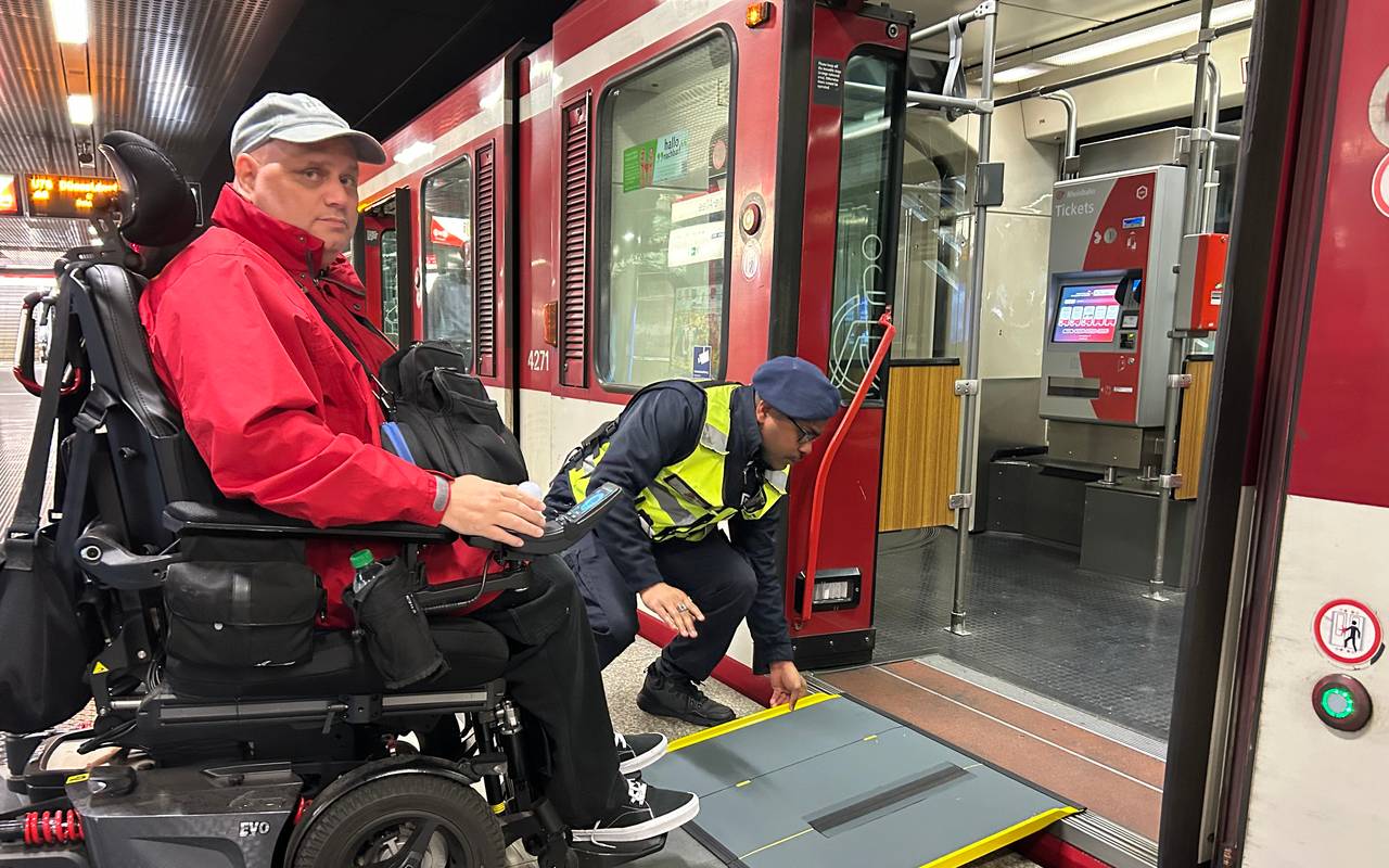 Ein Mann im Rollstuhl kann über eine mobile Rampe am Bahnsteig bequem in die U-Bahn einsteigen.