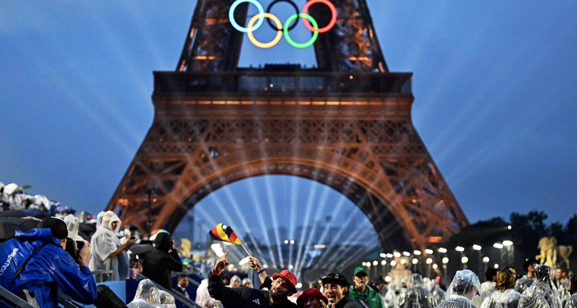 Eröffnungsfeier der Olympischen Sommerspiele, Mitglieder der deutschen Delegation kommen am Trocadero an, während der Eiffelturm und die Olympischen Ringe beleuchtet werden.