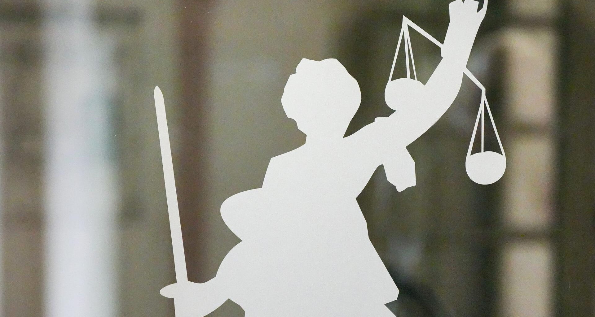Die Figur der Justitia mit Richtschwert und Waage ist auf dem Glasfenster einer Tür im Gerichtsgebäude zu sehen