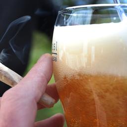 Eine Hand hält einen Joint neben einem Bierglas. (Quelle: dpa/Karl-Josef Hildenbrand)