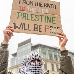 Symbolbild: Ein vermummter Mann hält ein Schild mit dem Slogan "From the river to the see, Palestine will be free!" hoch. (Quelle: imago images/Antoni)