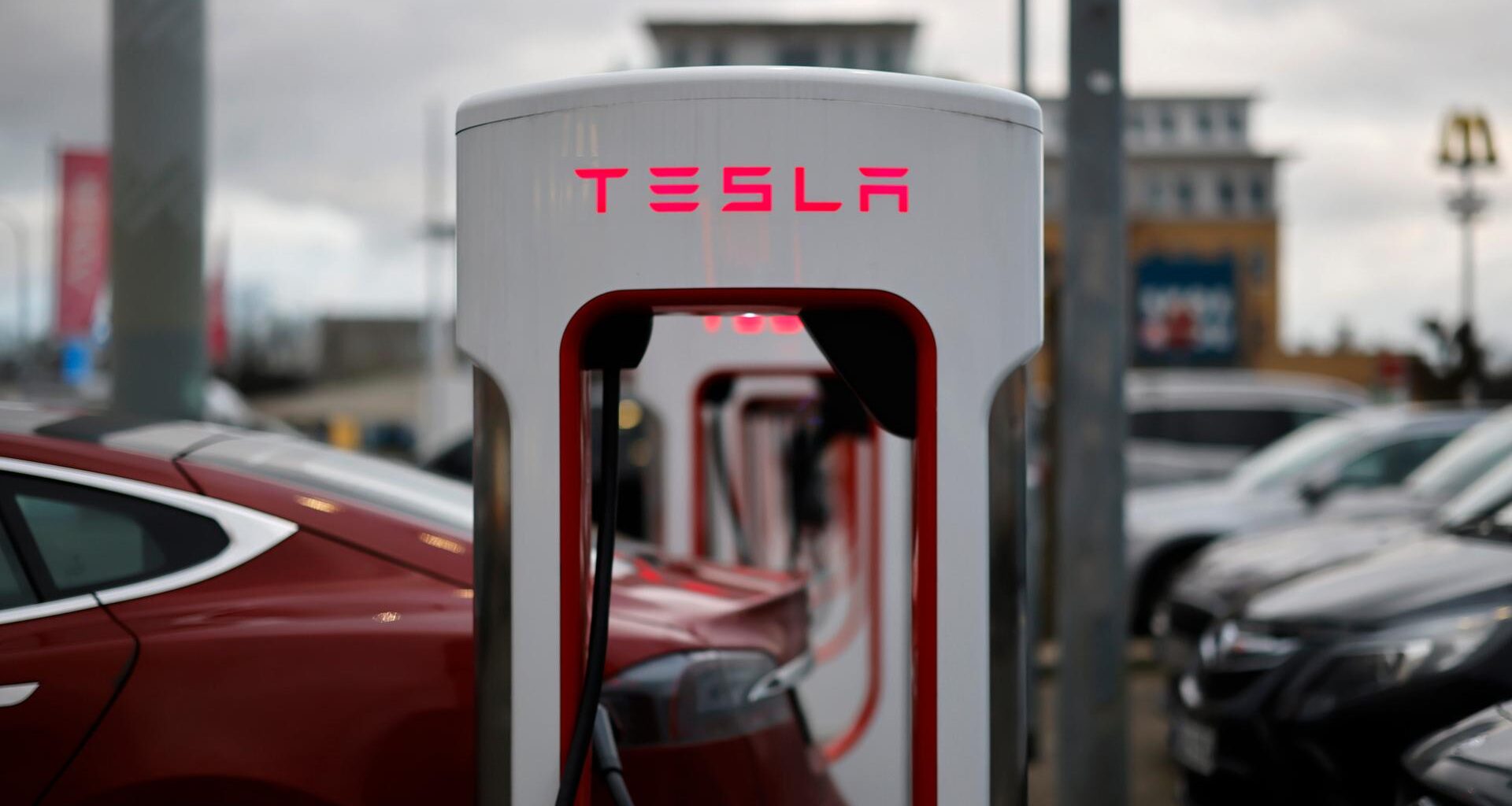 Ladestationen des E-Automobil-Herstellers TESLA für Elektroautos auf einem Parkplatz. Der Schriftzug TESLA leuchtet rot.