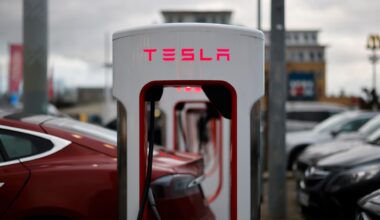 Ladestationen des E-Automobil-Herstellers TESLA für Elektroautos auf einem Parkplatz. Der Schriftzug TESLA leuchtet rot.