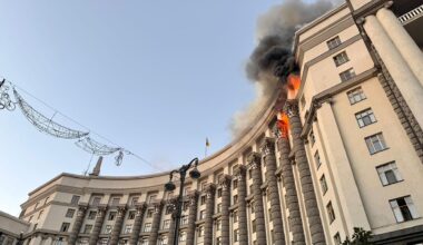 Blick von unten auf die Fassade des großen Gebäudes der ukrainischen Regierung, in der obersten Etage schlagen Flammen aus mehreren Fenstern.