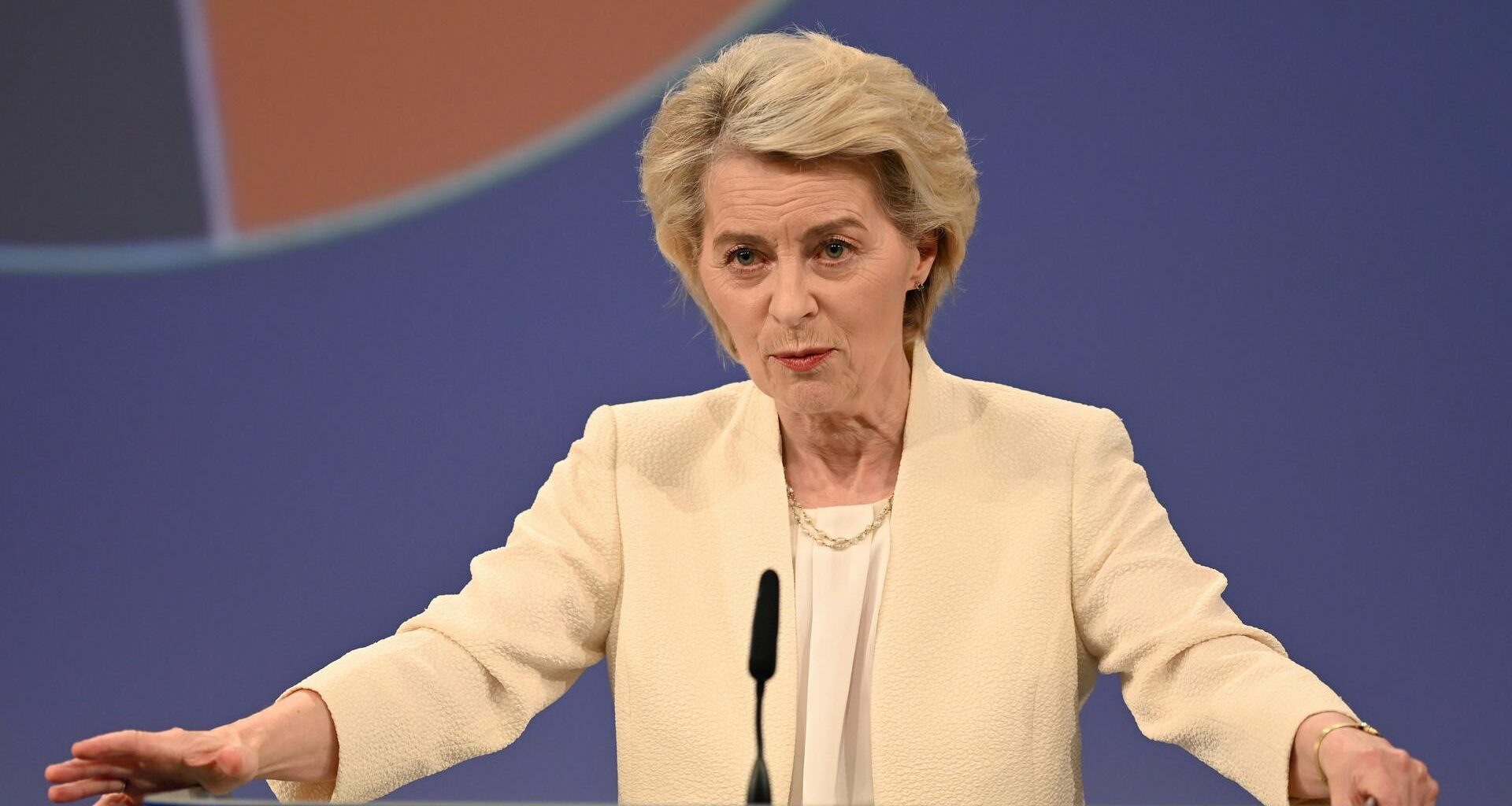 Ursula von der Leyen an einem Rednerpult. Sie hat die Hände an beiden Seiten des Pults aufgestützt. Sie schaut ernst.