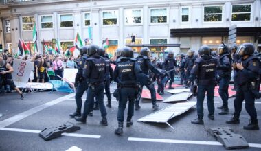 Polizisten in Einsatzkleidung steigen über umgestoßene Absperrgitter hinweg zu Demonstranten, die Palästina-Flaggen schwenken.