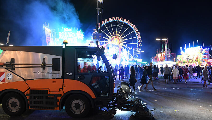 Ein Kehrfahrzeug der Stadtreinigung fährt bei Dunkelheit am Riesenrad vorbei. Nachts waren bis zu 30 Mitarbeiter unterwegs, damit morgens alles wieder sauber ist auf Wiesn.