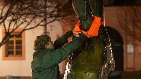 Die Figur des Bischof auf dem Mainzer Bischofsplatz hat in der Nacht zu Weiberfastnacht eine Warnweste von der Letzten Generation angezogen bekommen. 