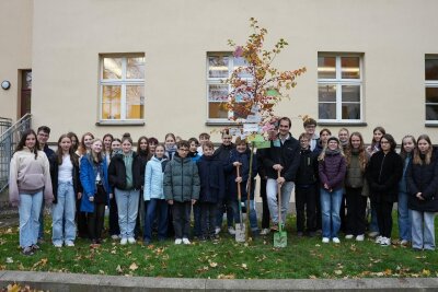 Schüler des Evangelischen Schulzentrums neben einem der Bäume mit Zukunftswünschen.