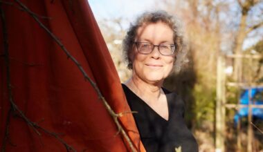 Katja Brandis steht vor einem roten Tuch in ihrem Garten