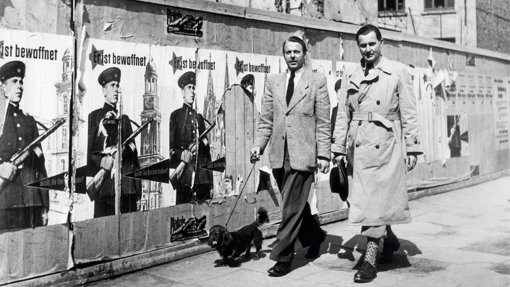 EVG-Vetrag: "Der Russe kommt": Im April 1953 spaziert der Gruppenleiter Heer im künftigen Verteidigungsministerium, Joachim Freyer (l.), an Werbeplakaten für die EVG in Bonn vorbei. Sie zeigen einen sowjetischen Soldaten vor deutschen Wahrzeichen.