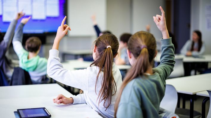 Schüler einer siebten Klasse melden sich in einem in einer Unterrichtsstunde. (Quelle: dpa/Matthias Balk)