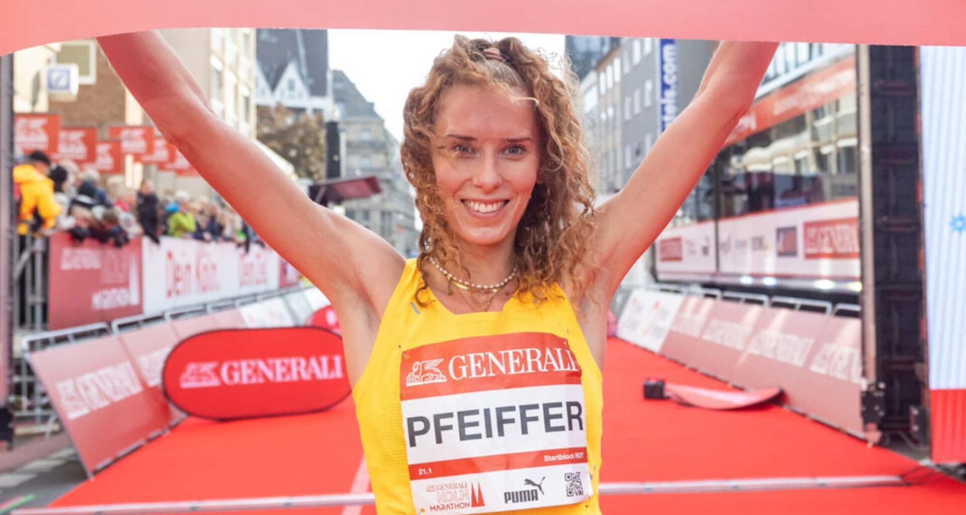 Zwei junge Frauen laufen bei sommerlichem Wetter auf einer Straße durch eine waldige Landschaft.