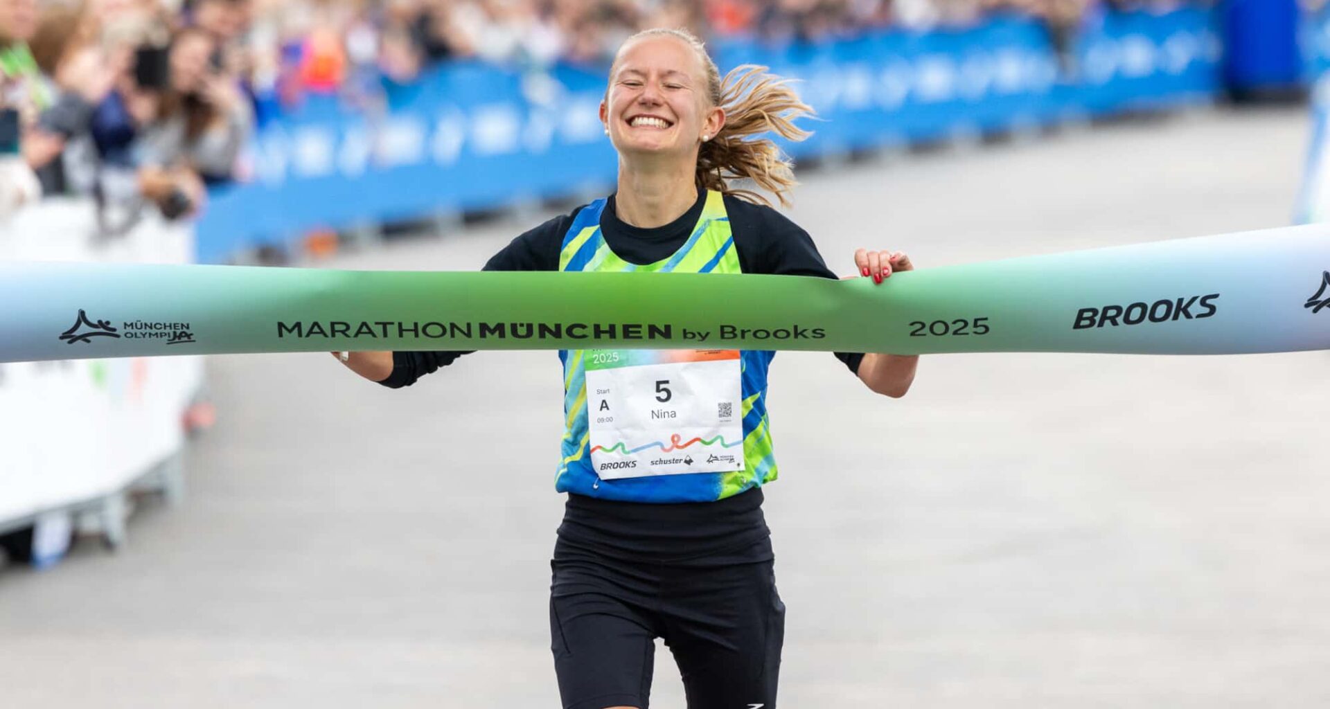 Zwei junge Frauen laufen bei sommerlichem Wetter auf einer Straße durch eine waldige Landschaft.