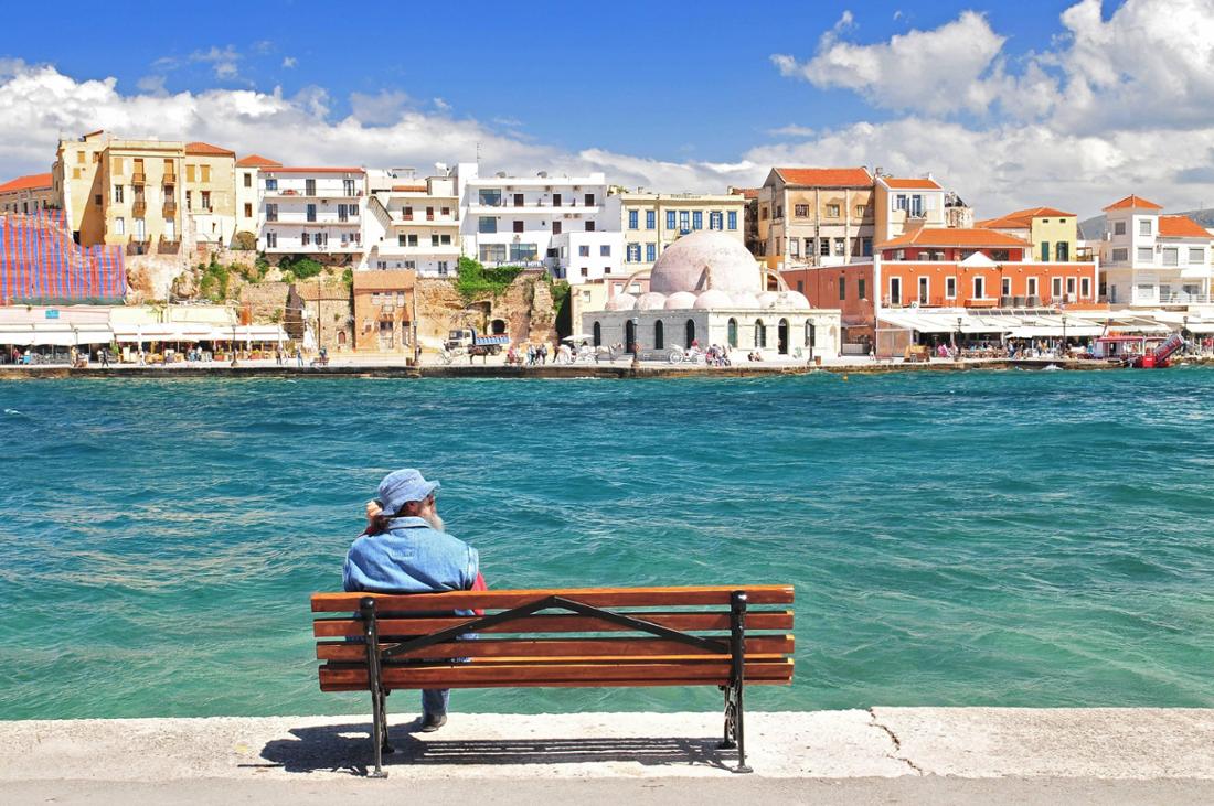 Man sitting on a bench in the Old Venetian Harbour Chania North West Coast Crete Greece