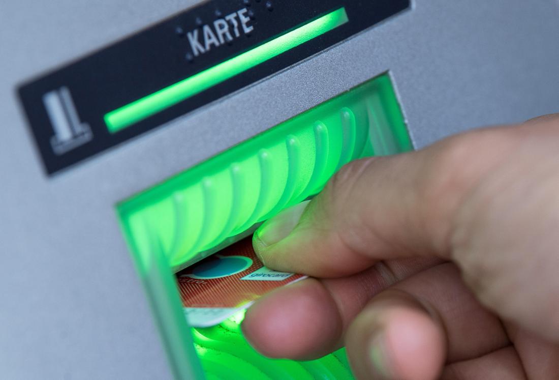 Eine Bankkundin steckt ihre Girokarte in einen Geldautomaten