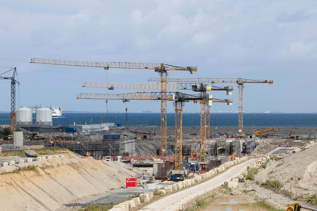 ARCHIV - 05.08.2025, Schleswig-Holstein, Fehmarn: Die Sonne scheint auf die Baustelle des Fehmarnbelt-Tunnels. Das 55,1 Milliarden Kronen (rund 7,4 Milliarden Euro) teure Bauwerk soll die dänische Insel Lolland mit der deutschen Insel Fehmarn verbinden und aus 89 Betonelementen bestehen. (zu dpa: „Projektgesellschaft: Fehmarnbelttunnel verzögert sich wohl“) Foto: Frank Molter/dpa +++ dpa-Bildfunk +++