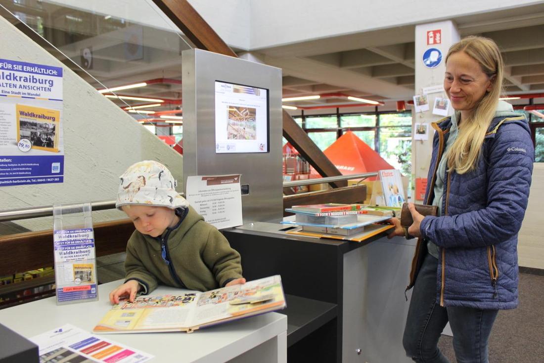 Mutter mit Kind bei der Ausleihe im Haus des Buches Waldkraiburg