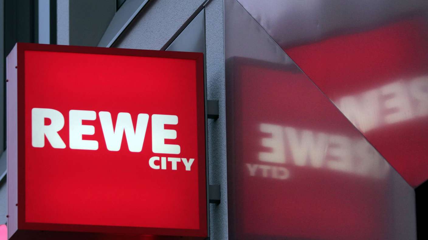 Leuchtreklame mit Schriftzug Rewe City an einer Filiale des Supermarktes