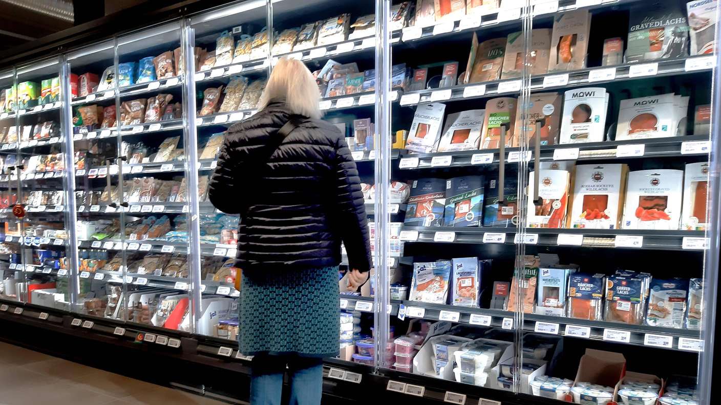 Eine Frau steht am Fischregal im Supermarkt