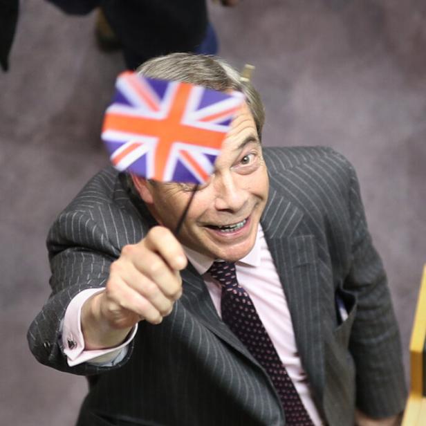 Nigel Farage hält eine kleine Union Flag hoch.
