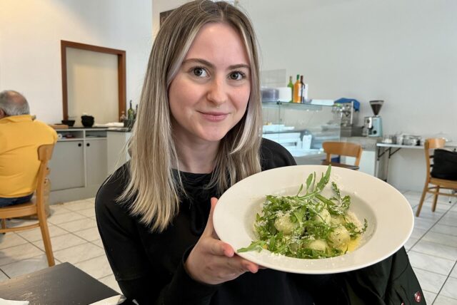 Ruhr-Nachrichten-Redakteurin Julia Segantini lächelt in die Kamera und hält einen Teller mit Gnocchi in die Kamera. Sie sitzt im Dortmunder Restaurant Pasta Buonissima.