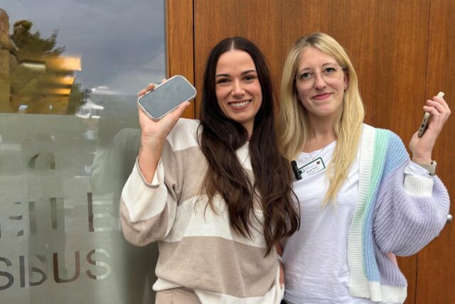 Denise Nonn und Leah Münch stehen vor dem Hospiz in Recklinghausen und halten ihre Handys in der Hand.