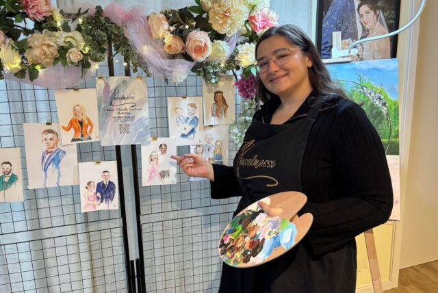 Patricia Radosevic steht vor ihren Bildern und hat eine Farbpalette in der Hand.