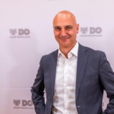 Dortmunds neuer Oberbürgermeister Alexander Kalouti steht vor einer Wand, auf der mehrfach das Logo der Stadt zu sehen ist.