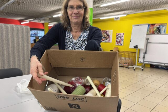 Petra Buschmann-Simons hält eine große Kiste in den Händen, in denen schon einzelne Kerzen und Wachsreste zu finden sind.