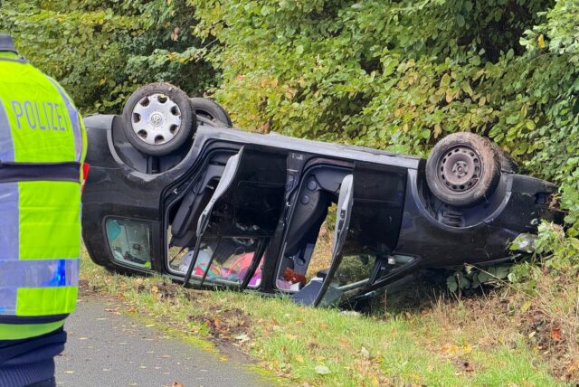 Ein schwarzes Auto liegt auf dem Dach in einem Grünstreifen neben einer Straße in Recklinghausen.