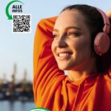 Eine junge Frau mit Kopfhöhrern dehnt ihre Arme sportlich hinter dem Nacken.