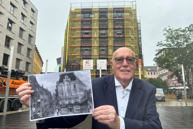 Thomas Ruhfus zeigt vor dem eingerüsteten Ruhfus-Haus ein historisches Bild des Gebäudes.