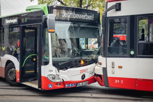 Bus steht mit zerstörter Front nach einem Unfall frontal vor einer Stadtbahn.