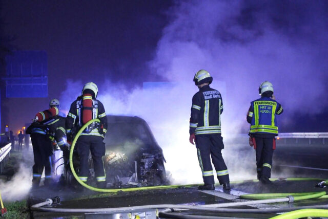 Mehrere Feuerwehrleute der Berufsfeuerwehr Herten bei einem Pkw-Brand auf der A2 bei Recklinghausen.
