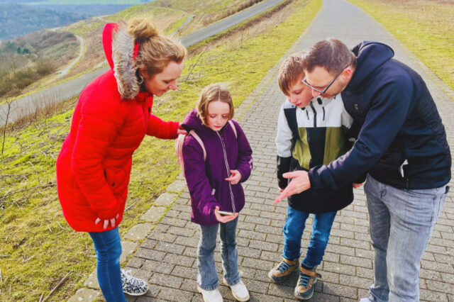 Eine Familie steht auf der Halde Hoheward in Herten-Süd und schaut auf ein Handy.