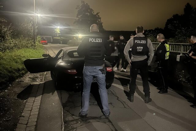 Polizisten stehen in Herdecke hinter einem Porsche.