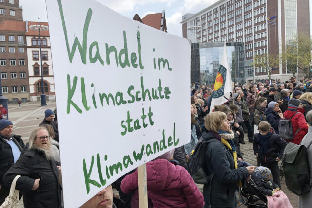 Demonstranten auf dem Friedensplatz fordern auf einem Transparent mehr Einsatz für den Klimaschutz.