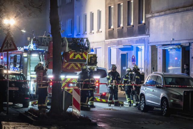 Feuerwehrleute stehen bei einem Kellerbrand vor dem betroffenen Haus.