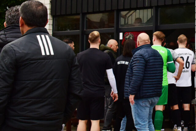 Spieler und Verantwortliche stehen vor dem Kabinengebäude des TuS Haltern