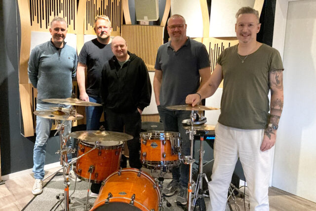 Die Hertener Toby Schwietering, Tobias Mengede, Andreas Kurth, Tim Jansen und Marcus Ugljanin (von links) stehen in einem Probenraum um ein Schlagzeug herum.