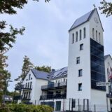 Weiß gestrichene Kirche mit Turmspitze, die in den blauen Himmel ragt.