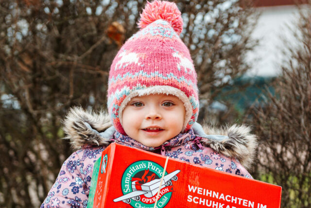 Ein Kind hält einen Karton der Aktion in den Händen.