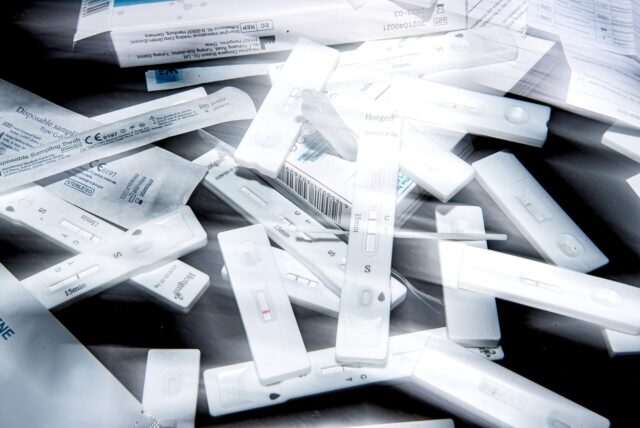 Zahlreiche Corona-Schnelltest liegen auf einem Tisch.