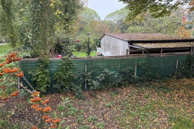 Man sieht ein Scuhld der Kleingartenanlage Nord und im Hintergrund Bäume.