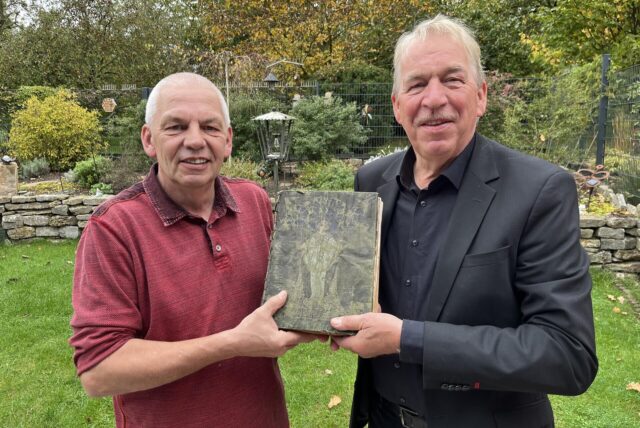 Dirk Horn und Theo Huting halten ein Kirchenbuch in den Händen.