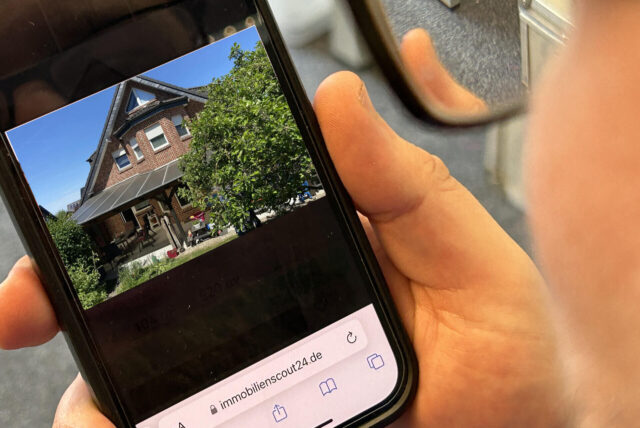Ein Mann schaut sich ein Inserat auf Immoscout auf dem Smartphone an.