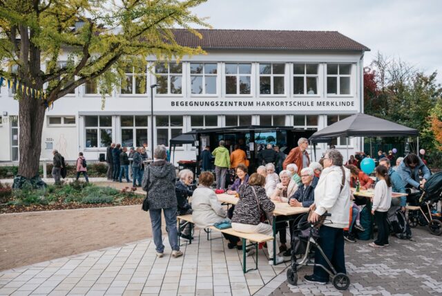 Viele Besucherinnen und Besucher feiern vor dem Begegnungszentrum Harkortschule Merklinde die Eröffnung des neuen Quartiersplatzes.